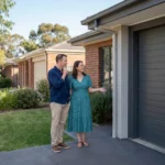 A husband and wife in stand in a suburban Australian driveway, thoughtfully looking at a modern roller garage door as part of their home lifestyle decision in roller door selection.